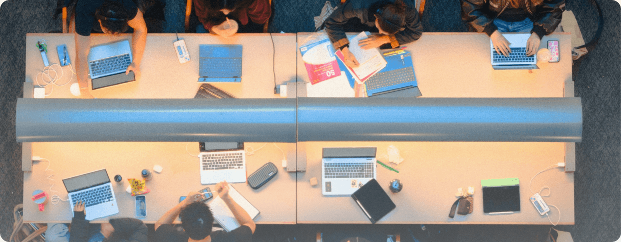 Students working on laptops around a shared study table